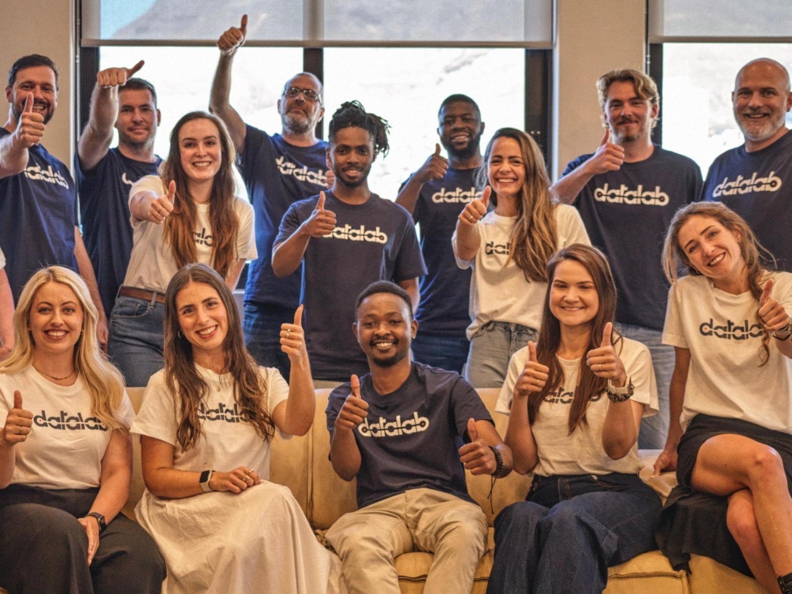 The full Datalab team in branded navy and white t-shirts giving thumbs up together