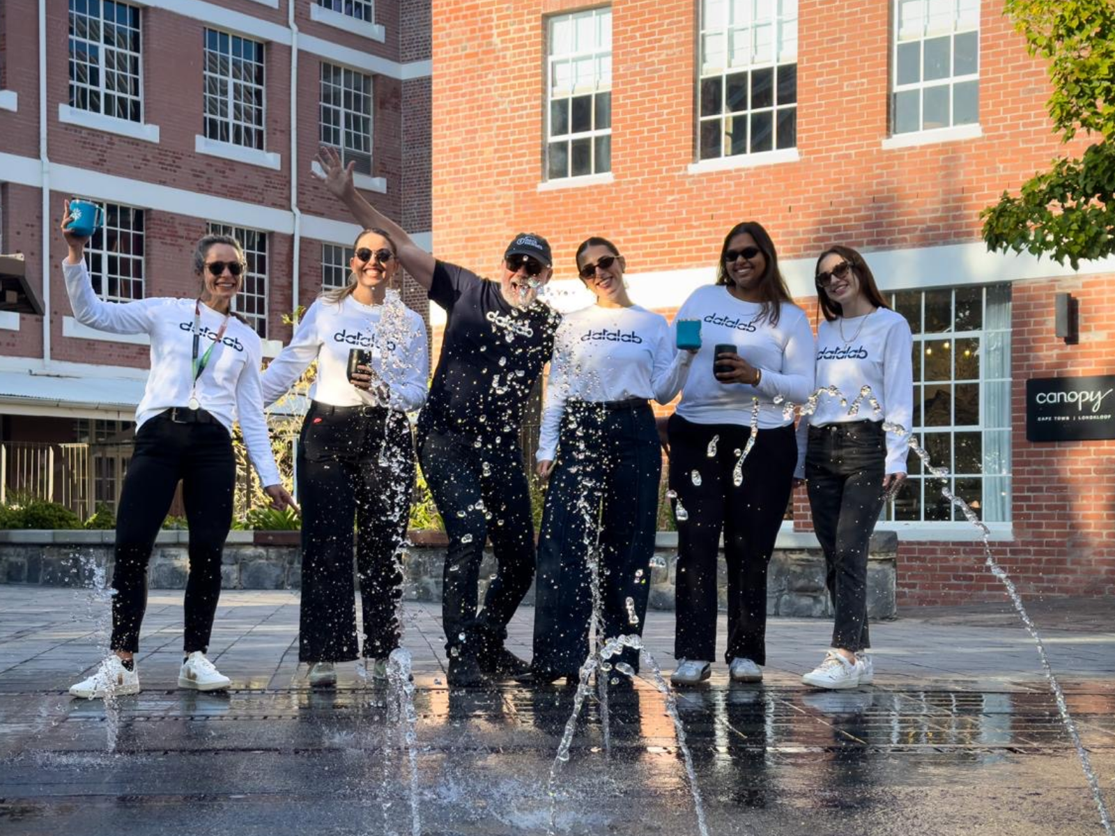 Datalab team celebrating outdoors in matching white Datalab-branded hoodies on T-shirt Tuesday