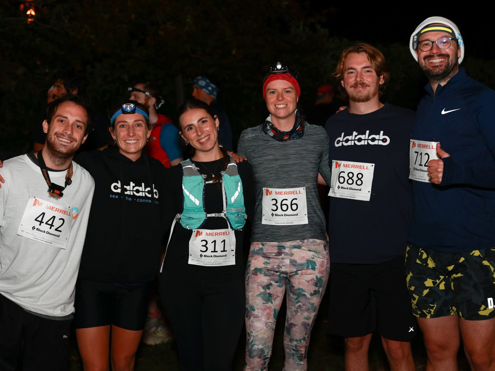 Datalab team members at a night trail run wearing race bibs and Datalab branded gear