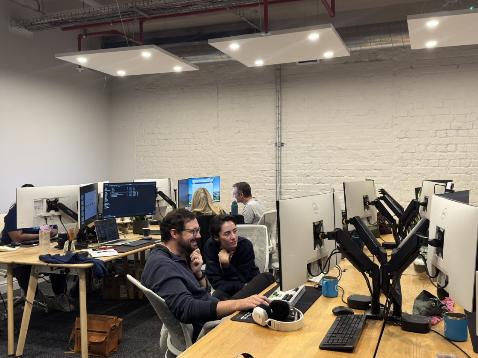 Two Datalab colleagues collaborating at multi-monitor workstations in the Cape Town office